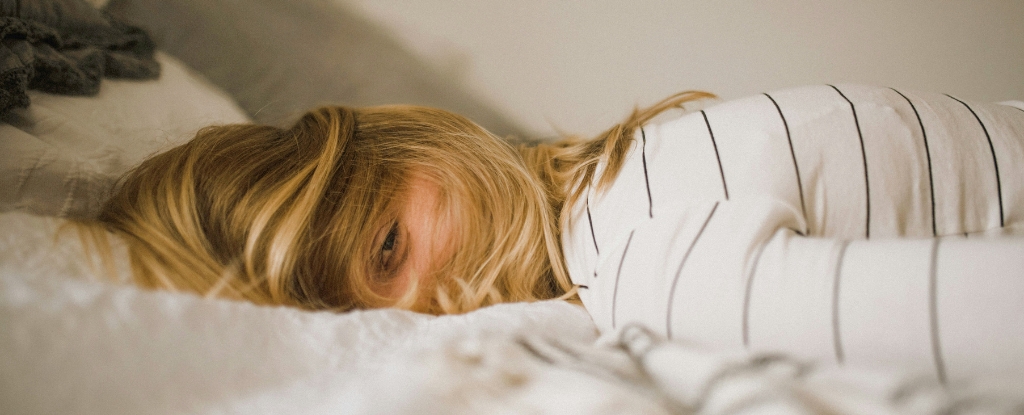 WomanLyingDefeatedlyInBedPeeringThroughHairDrapedOverEyes.jpg